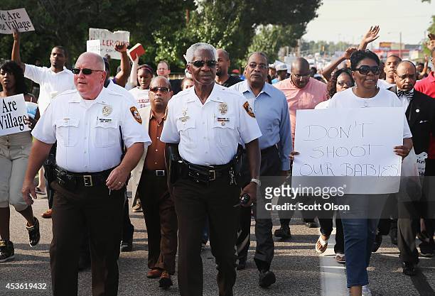 Police officers march with demonstrators protesting the shooting death of teenager Michael Brown on August 14, 2014 in Ferguson, Missouri. Brown was...