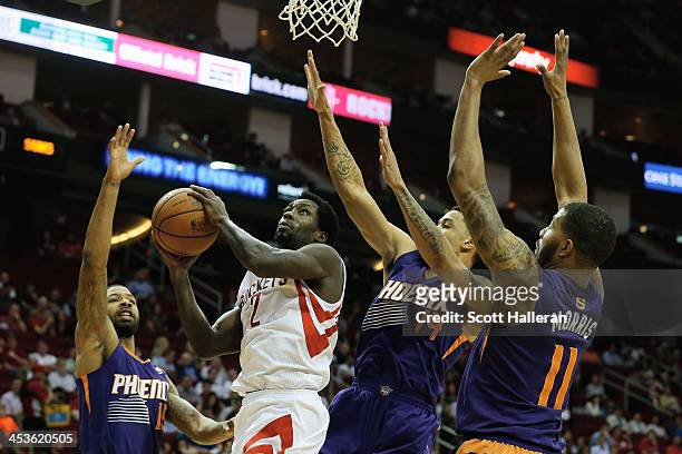 Patrick Beverley of the Houston Rockets takes a shot as he is defended by Marcus Morris, Gerald Green and Markieff Morris of the Phoenix Suns at...