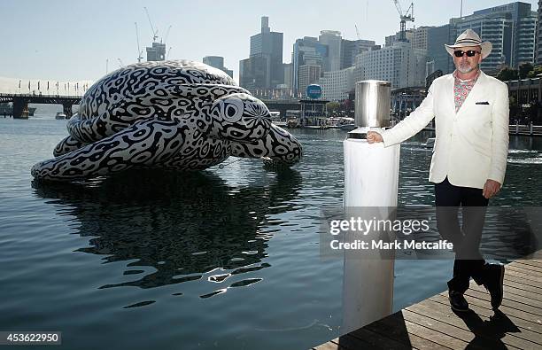 Artist BJ Price poses in front of a 5 metre tall, 15 metre long Sea Turtle that is emblazoned with his artwork 'Alpha" at Darling Harbour on August...