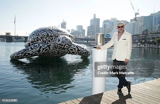 Artist BJ Price poses in front of a 5 metre tall, 15 metre long Sea Turtle that is emblazoned with his artwork 'Alpha" at Darling Harbour on August...