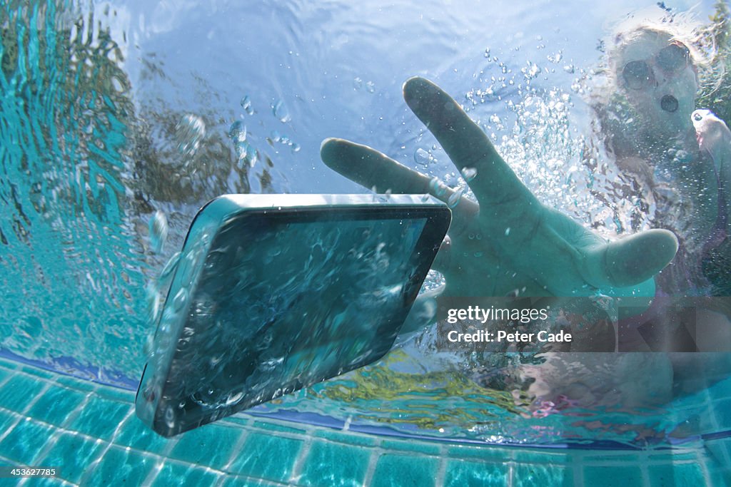 Woman dropping phone into swimming pool