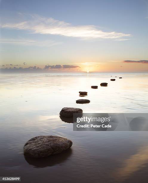 stepping stones over water at sunrise - stepping stone stock-fotos und bilder