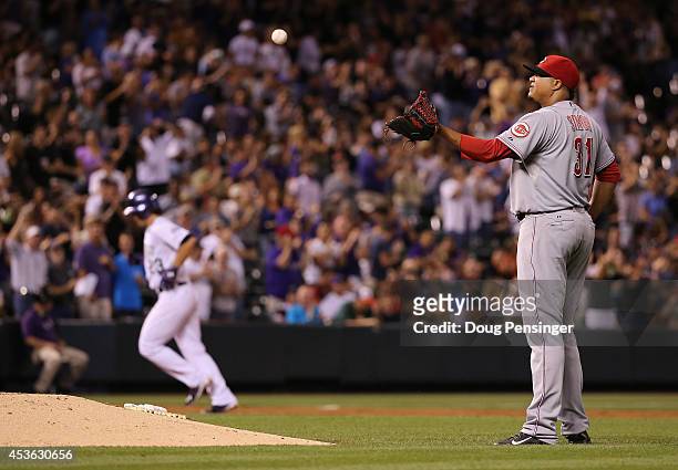 Starting pitcher Alfredo Simon of the Cincinnati Reds collects the ball after giving up a three run home run to Charlie Culberson of the Colorado...