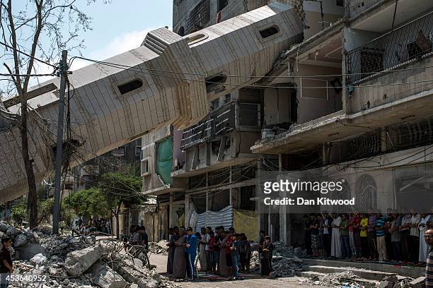 Palestinians attend Friday noon prayers in the shadow of a toppled minaret at Al-Susi Mosque on August 15, 2014 in Gaza City, Gaza. A new five-day...