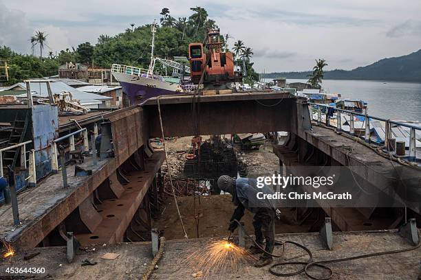Workman cuts through the deck of a large ship that is being broken down for scrap after it was pushed ashore by Typhoon Yolanda in the township...