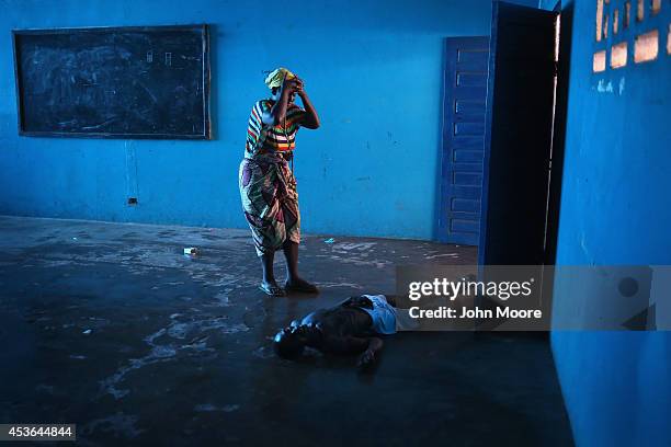 Omu Fahnbulleh stands over her husband Ibrahim after he staggered and fell, knocking him unconscious in an Ebola ward on August 15, 2014 in Monrovia,...