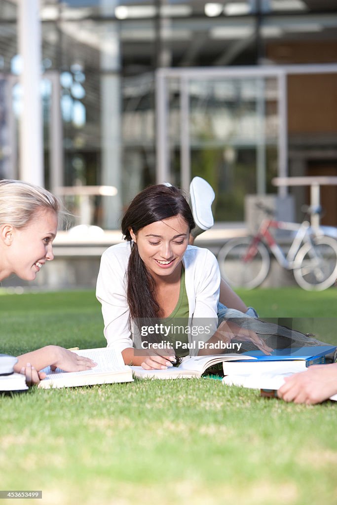 Group of Young Women laying down on grass with books outdoors