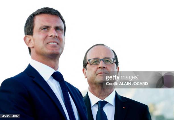 French President Francois Hollande and French Prime minister Manuel Valls, look at planes of the "Patrouille de France" flying over, on August 15,...