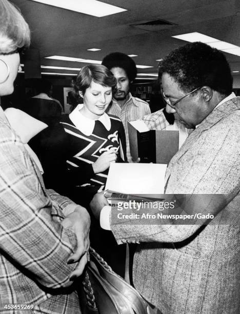 Author Alex Haley signs a copy of his book Roots, 1977.