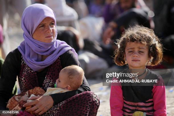 Yazidi Iraqi woman sits with her children at the Bajid Kandala camp near the Tigris River, in Kurdistan's western Dohuk province, where they took...