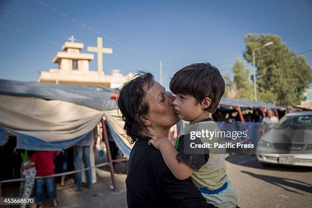 Woman kisses her son outside the Mar Tshmony church. 500 Christian families have been sheltered at Mar Tshmony church, after an unprecedented ISIS...