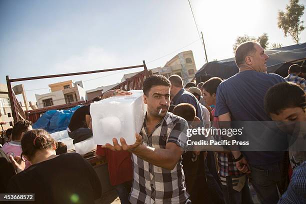 Man carries his ice block ration. 500 Christian families have been sheltered at Mar Tshmony church, after an unprecedented ISIS advance into Kurdish...