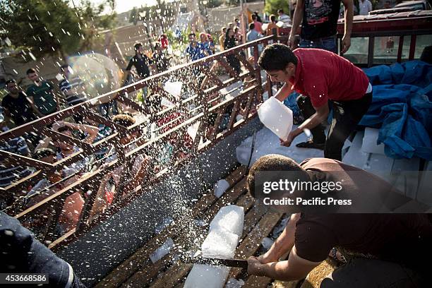 Volunteers cut ice blocks for the refugees in Mar Tshmony church. 500 Christian families have been sheltered at Mar Tshmony church, after an...