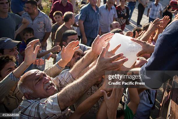 Volunteers distribute ice blocks for the refugees in Mar Tshmony church. 500 Christian families have been sheltered at Mar Tshmony church, after an...