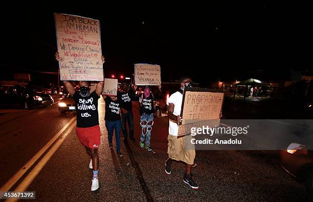 Demonstrators hold up signs as they gather at West Florissant Avenue to protest the shooting death of Michael Brown by a police officer in Ferguson,...