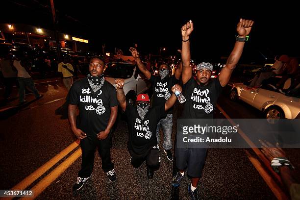 Demonstrators raise their hands as they gather on West Florissant Avenue to protest the shooting death of Michael Brown by a police officer in...