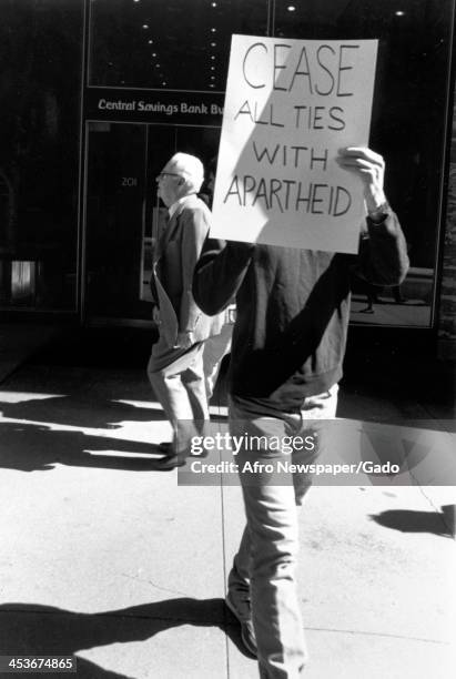 Protestors march holding signs in support of ending South African apartheid, 1980.