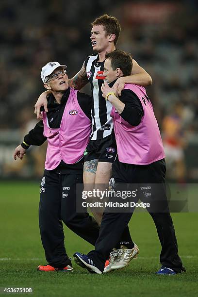 Dayne Beams of the Magpies is helped off after a leg injury during the round 21 AFL match between the Collingwood Magpies and the Brisbane Lions at...