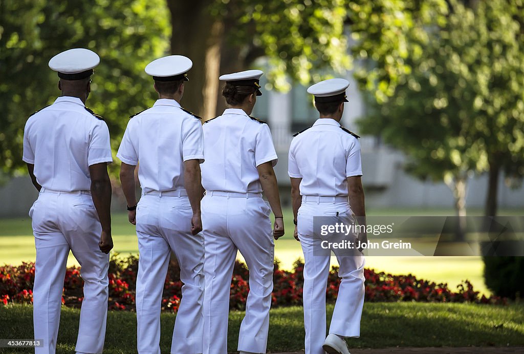 Cadets in sevice whites march on the campus of the US Naval...