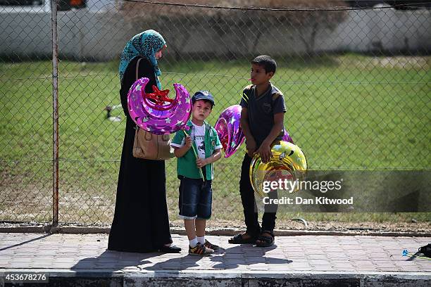 Woman buys a balloon from a balloon seller on August 16, 2014 in Gaza City, Gaza. A five-day ceasefire between Palestinian factions and Israel...
