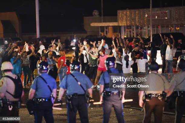 Missouri State Highway Patrol officers listen to taunts from demonstrators during a protest over the death of Michael Williams on August 15, 2014 in...