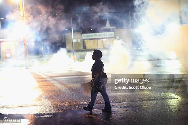 Demonstrator walks through smoke launched by police after a skirmish on August 15, 2014 in Ferguson, Missouri. Police sprayed pepper spray, shot...