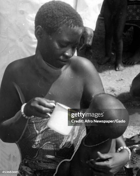 An African mother in feeds milk sent by UNICEF to her infant in order to alleviate kwashiorkor, Nutangu Village , Democratic Republic of the Congo,...