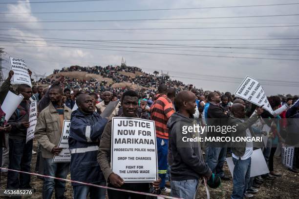 Man holds a placard reading "Justice now for Marikana, Prosecute police now, Drop the charges, Fight for the living wage" as people attend on August...