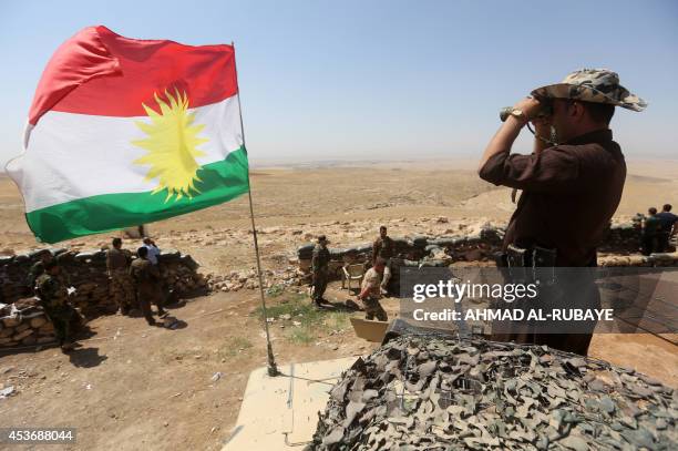 Flag of the autonomous Kurdistan region flies as Iraqi Kurdish Peshmerga fighters take position to monitor the area from their front line post in...