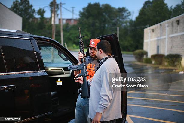 Business owners carry assault weapons to protect their grocery store, Sam's Meat Market, after another night of rioting and looting following...