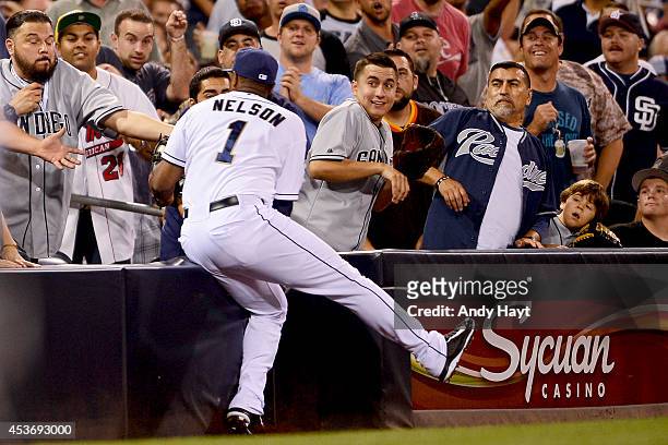 Chris Nelson of the San Diego Padres heads into the stands as he makes the catch on a foul ball hit by Charlie Blackmon of the Colorado Rockies...