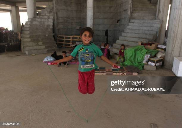 An Iraqi Yazidi girl, who fled her home when Islamic State militants attacked the town of Sinjar, skips inside a building under construction where...