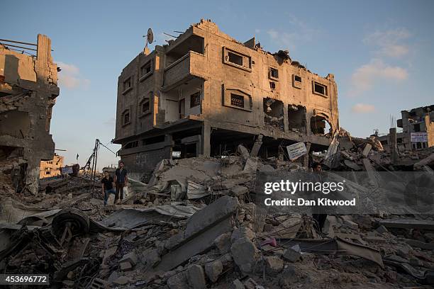 Palestinian men stand amongst the rubble of a destroyed area of housing on August 16, 2014 in Gaza City, Gaza. A five-day ceasefire between...