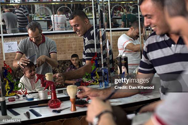 Young boy cries as he has his hair cut in a barber on August 16, 2014 in Gaza City, Gaza. A five-day ceasefire between Palestinian factions and...