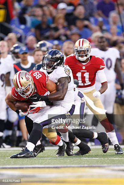 Vance McDonald of the San Francisco 49ers is tackled by C.J. Mosley of the Baltimore Ravens during the game at M&T Bank Stadium on August 7, 2014 in...