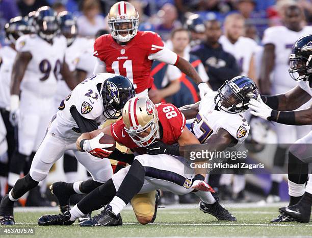 Vance McDonald of the San Francisco 49ers is tackled by C.J. Mosley and Chykie Brown of the Baltimore Ravens during the game at M&T Bank Stadium on...