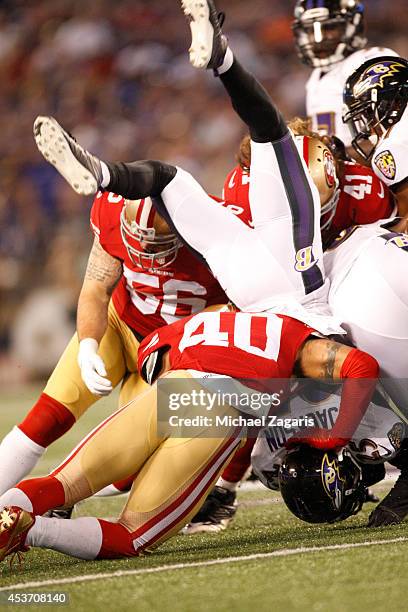 Asa Jackson of the Baltimore Ravens is upended by Darryl Morris of the San Francisco 49ers during the game at M&T Bank Stadium on August 7, 2014 in...
