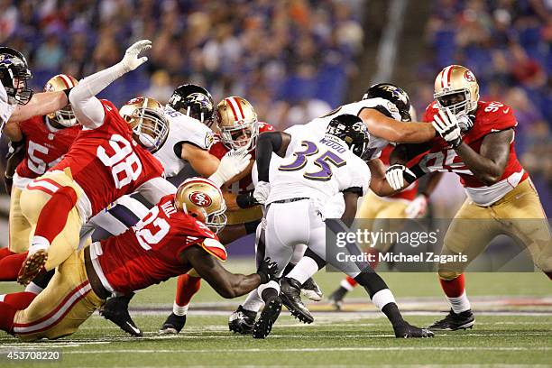 Lawrence Okoye and Quinton Dial of the San Francisco 49ers tackle Cierre Wood of the Baltimore Ravens during the game at M&T Bank Stadium on August...