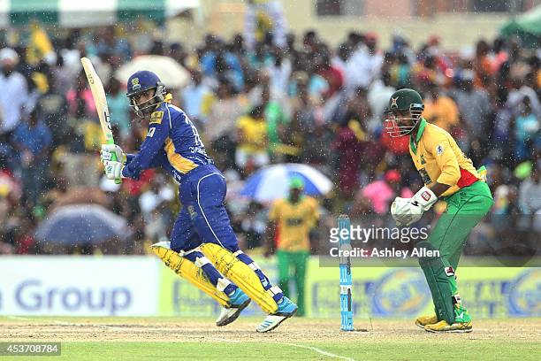 Shoaib Malik of Barbados Tridents hits the ball as Denesh Ramdin looks on during the Limacol Caribbean Premier League 2014 final match between Guyana...