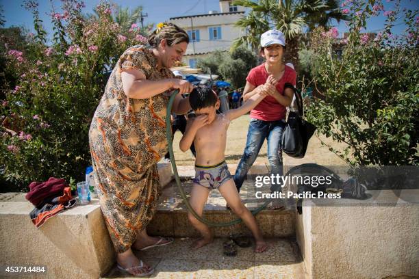 Kurdish mother gives her son a shower while his sister laughs as 650 Kurdish Christian families have taken shelter inside Saint Joseph Church, after...