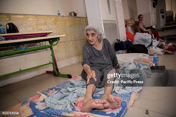 An elderly Kurdish woman sits on a mattress she has been allocated. 650 Christian families have taken shelter inside Saint Joseph Church, after an...