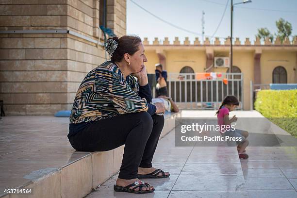 Kurdish woman sits on the stairs outside Saint Joseph Church. 650 Christian families have taken shelter inside Saint Joseph Church, after an...