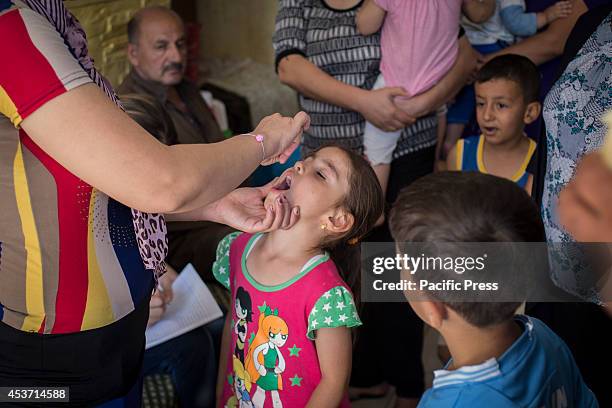 Kurdish child receives a poliomyelitis vaccine at Saint Joseph Church. 650 Christian families have taken shelter inside Saint Joseph Church, after an...