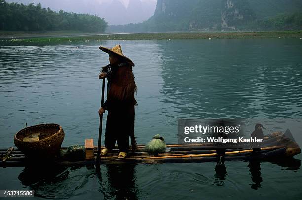 China, Guangxi Province, Near Guilin, Xing Ping, Li River, Rain, Fisherman On Bamboo Raft, Cormorants.