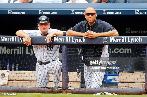 Derek Jeter and first base coach Mick Kelleher of the New York Yankees looks on from the dugout during the second inning against the Texas Rangers at...