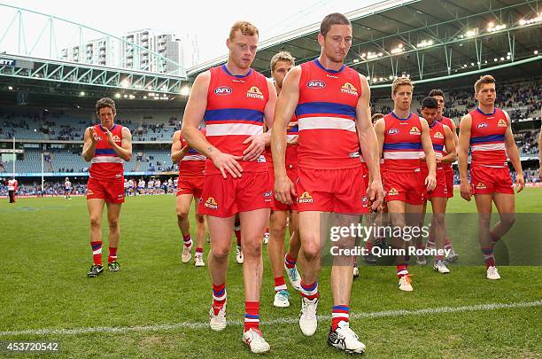 Adam Cooney, Matthew Boyd and their Bulldogs team mates look dejected as they leave the field after losing the round 21 AFL match between the North...