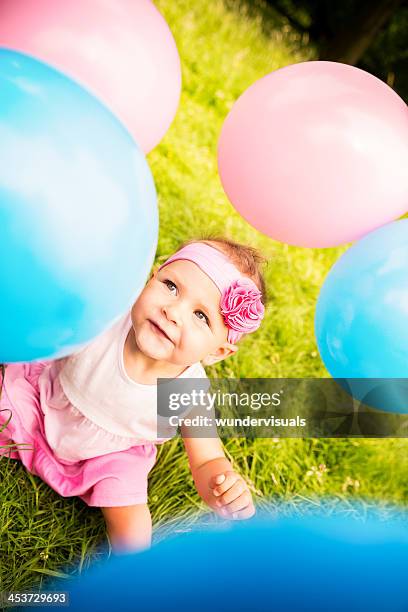 baby in garden playing with balloons having fun - alleen één babymeisje stockfoto's en -beelden