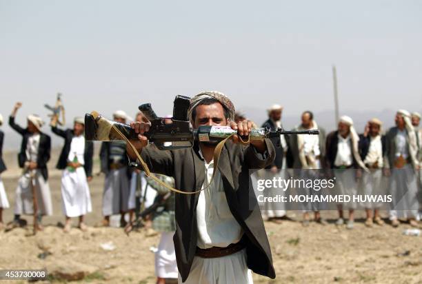 An armed Yemeni man loyal to the Shiite Huthi movement holds up his gun during a tribal gathering against al-Qaeda militants in the Bani al-Harith...