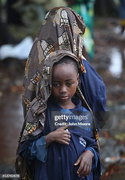 Elija Siafa stands in the rain with his sister Josephine while waiting outside the new Doctors Without Borders , Ebola treatment center on August 17,...