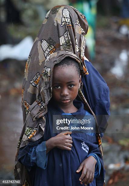 Elija Siafa stands in the rain with his sister Josephine while waiting outside the new Doctors Without Borders , Ebola treatment center on August 17,...